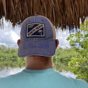 A man wearing a blue hat standing under an umbrella.