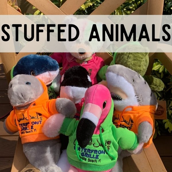 Stuffed animals in a basket on top of a wooden bench.