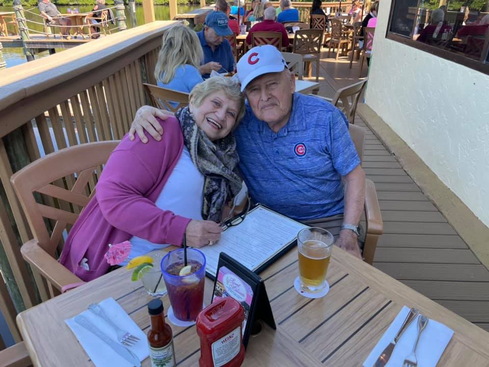 A man and woman sitting at an outdoor table with drinks.