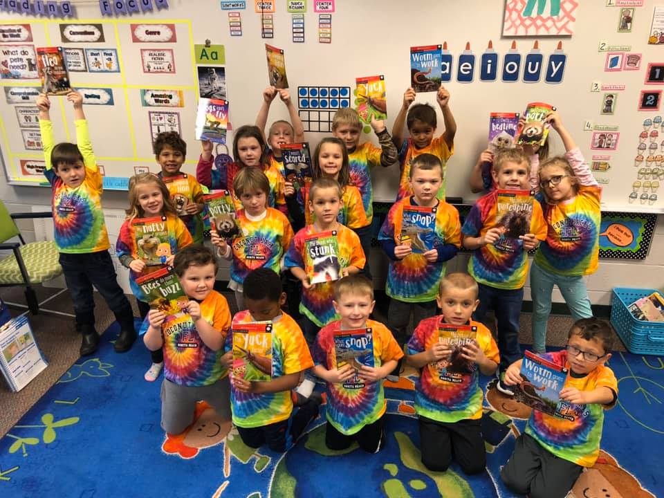 A group of children holding books in front of their faces.