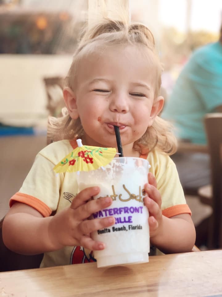 A child drinking from a cup with straw.