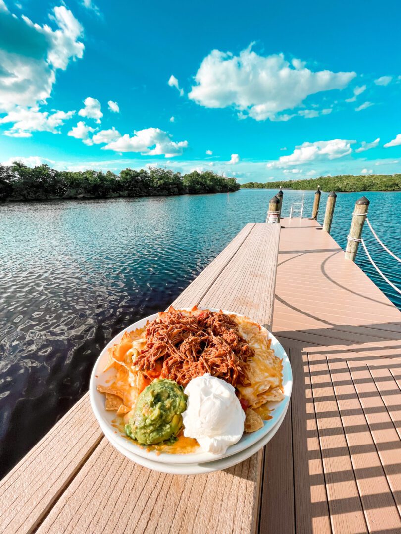 A bowl of food on the dock near water.