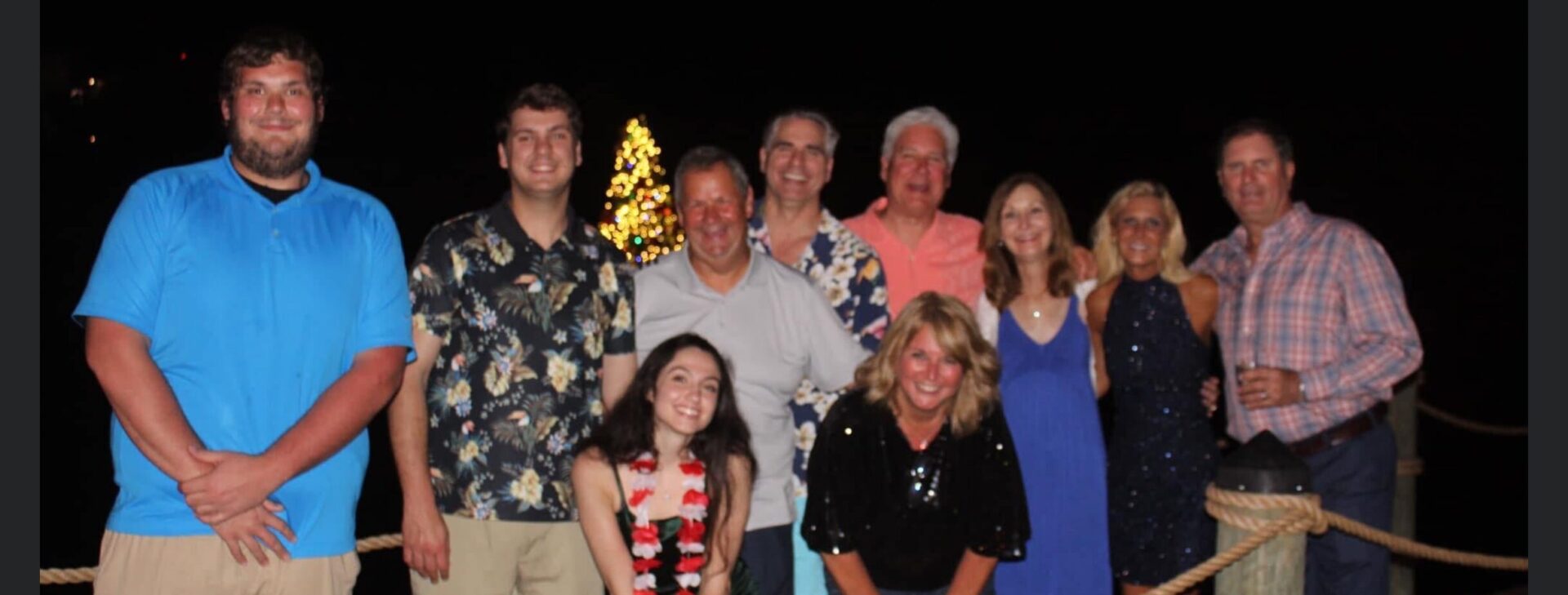 A group of people standing in front of a christmas tree.