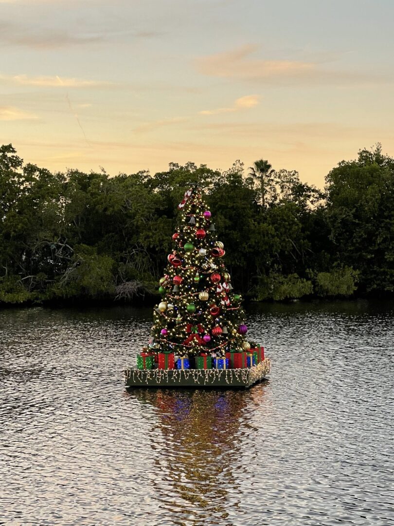 A boat with christmas tree on it in the middle of water.