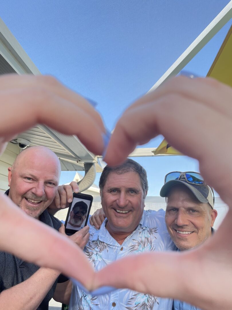 Three men are taking a picture of themselves with their cell phone.