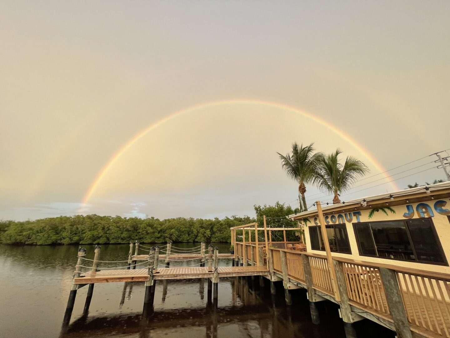 A rainbow over the water and pier.