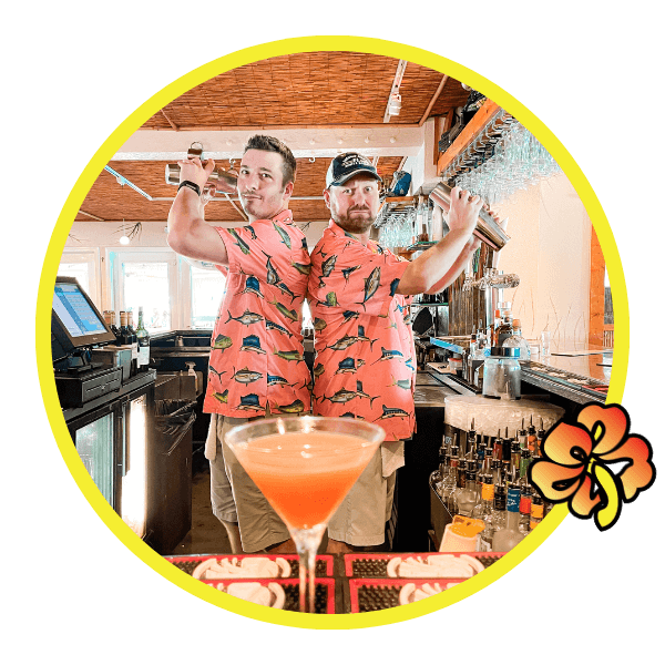 Two men in matching shirts and hats holding drinks.
