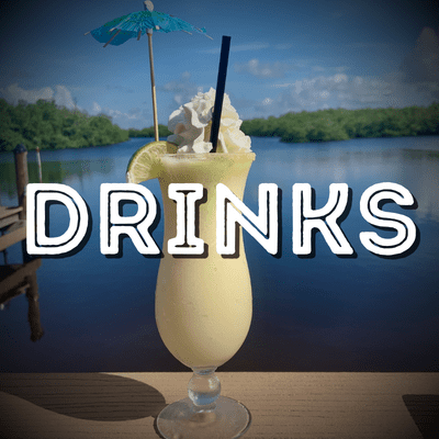 A drink is sitting on the table by the water.