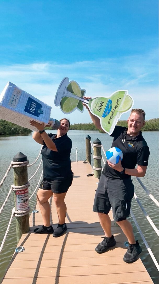 Two people standing on a bridge holding up items.