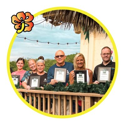 A group of people holding up certificates in front of a palm tree.