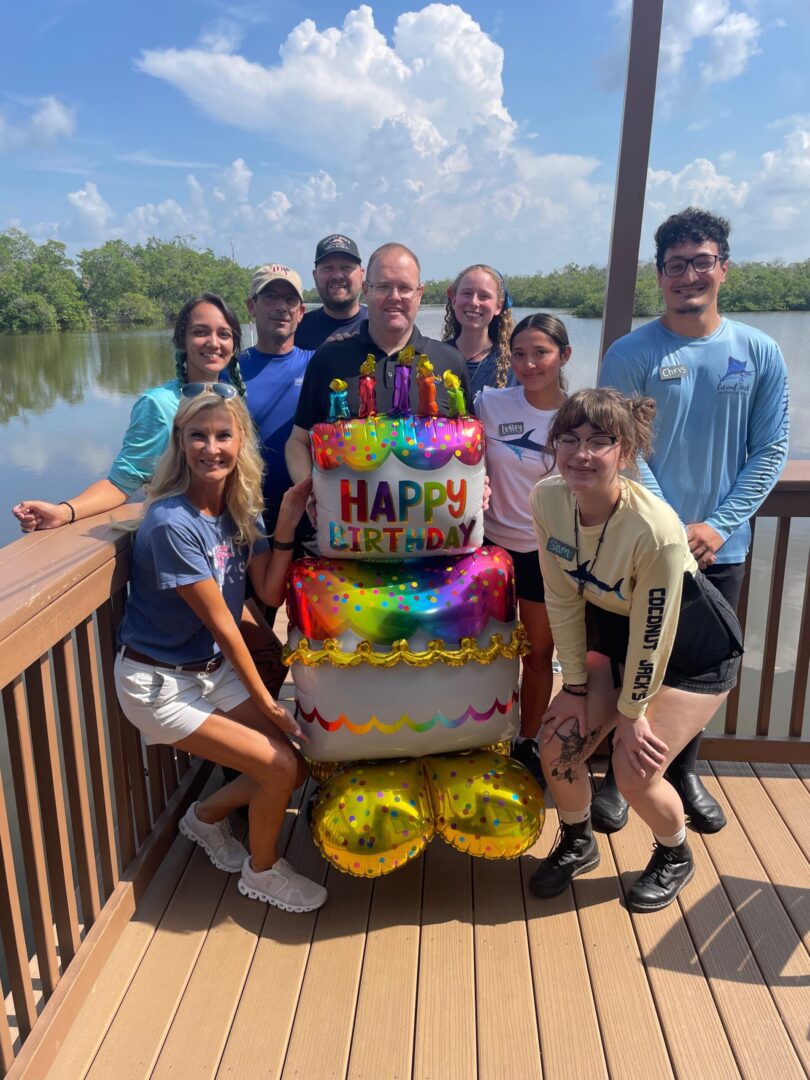A group of people standing around a cake.