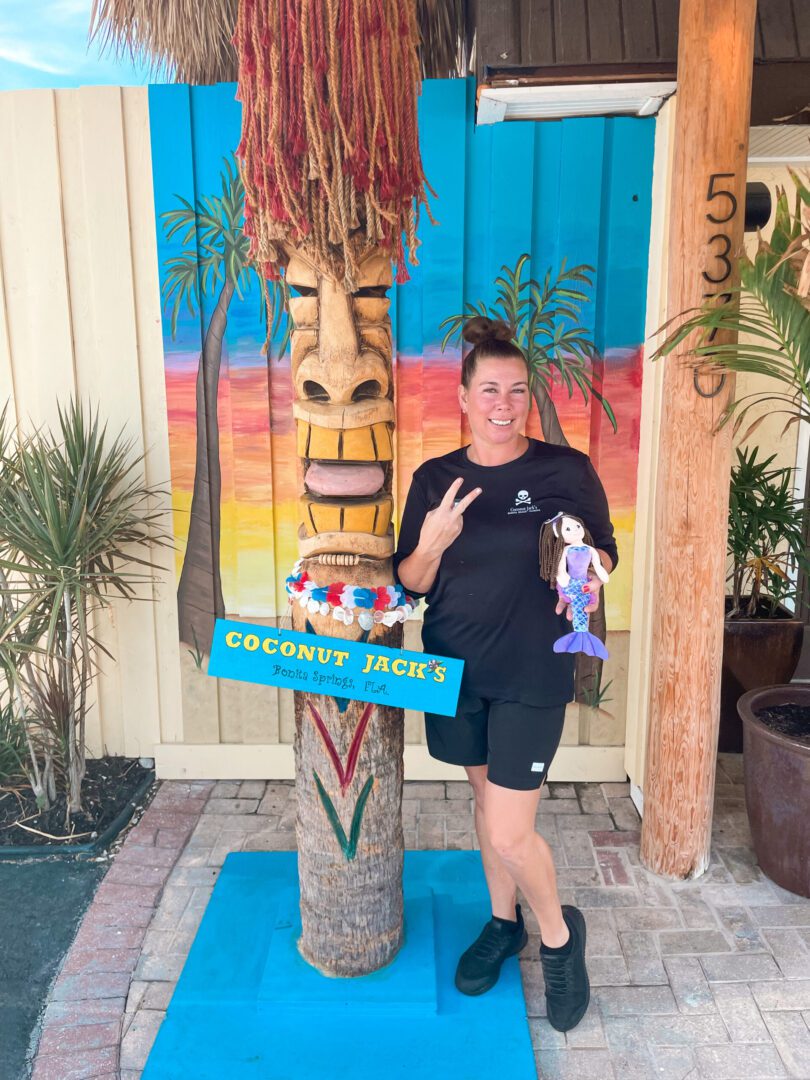 A woman standing next to an outdoor tiki statue.