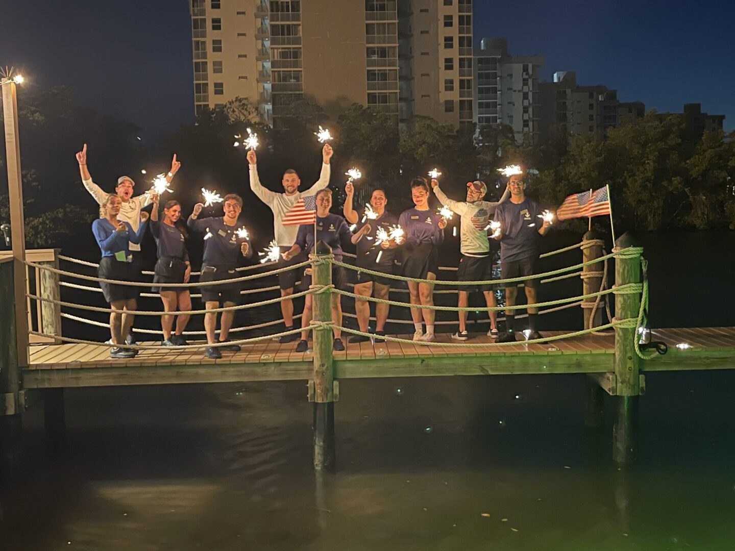 A group of people holding sparklers on top of a bridge.
