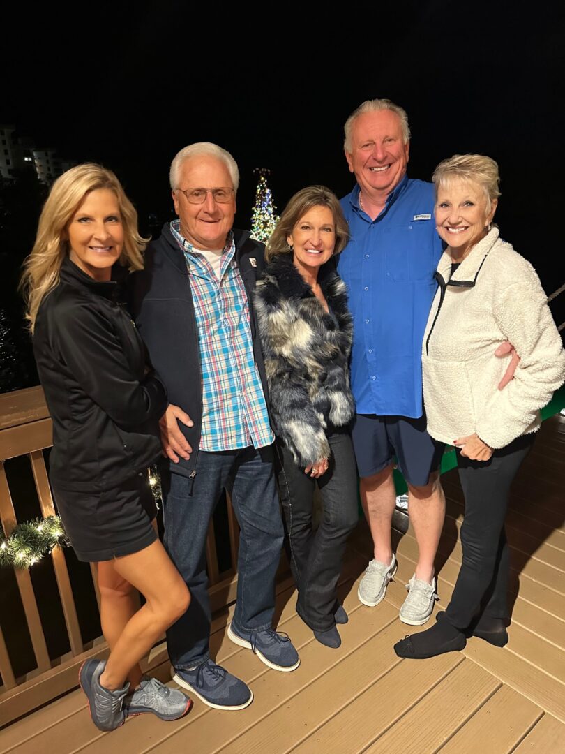 A group of people standing on top of a wooden deck.