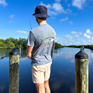 A man standing on the dock holding a fishing rod.